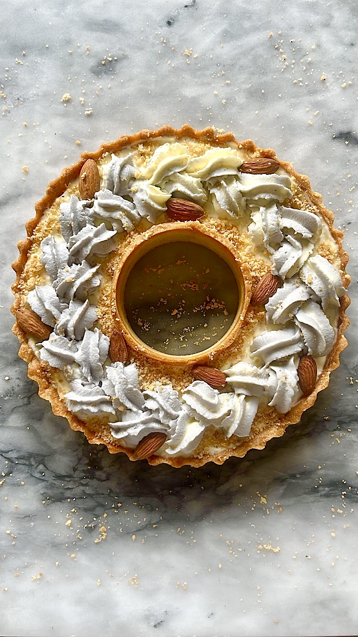 Tart ring topped with grey heart-shaped cream, decorated with almonds.